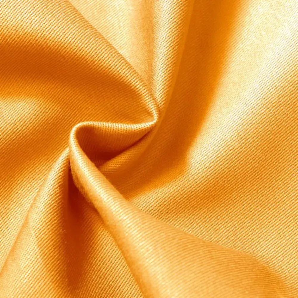 Tecido brim leve com uma coloração vibrante amarelo ouro, com uma textura diagonal característica e um caimento suave.