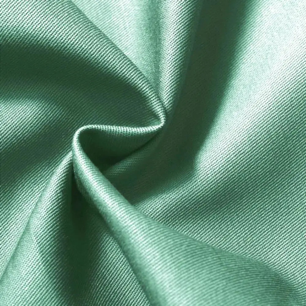 Tecido de brim leve em um tom de verde vivo, com textura proeminente e uma estrutura que sugere conforto e durabilidade.