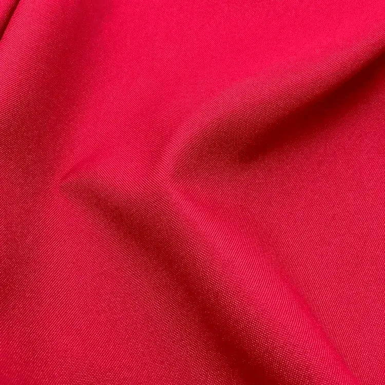 tecido Oxford liso na cor vermelha, com uma textura sutil e uma dobra suave que cria um padrão de sombra delicado.