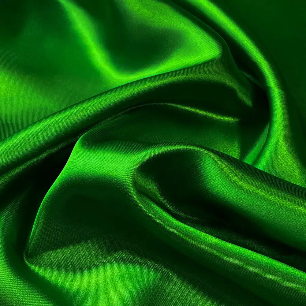 Tecido de cetim verde bandeira com textura sedosa e brilho vibrante, evidenciando uma superfície suave e luxuosa.