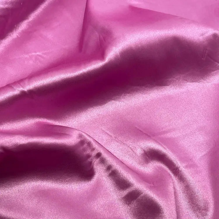 Tecido de cetim com elastano em rosa chiclete, com uma superfície sedosa e brilhante, enfatizando as dobras fluidas que demonstram a qualidade do material.