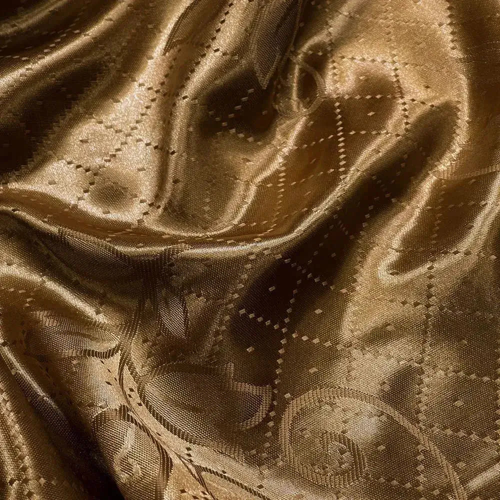 ecido satin jacquard na cor ouro velho com padrão de pontos sutis e desenho abstrato que formam uma superfície dinâmica.